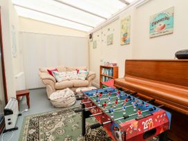 A room with a foosball table a piano a beige sofa with pillows a bookshelf and a patterned rug at Haffannedd in Rhos-On-Sea