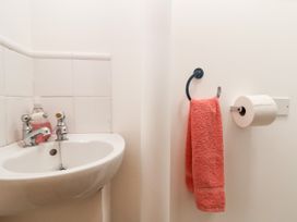 A small bathroom sink with faucet soap bottle pink hand towel on towel ring and toilet paper roll on holder at Haffannedd in Rhos-On-Sea