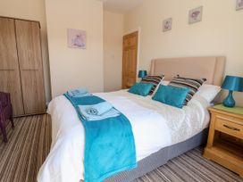 A bedroom with a bed with blue cushions and blankets bedside tables with lamps a wardrobe and a chair at Haffannedd in Rhos-On-Sea