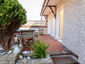 An outdoor patio with a brick floor wooden table and chairs a tree and plants outside a building at Haffannedd in Rhos-On-Sea