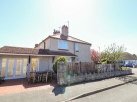 A corner house with a fenced garden and outdoor wooden table at Haffannedd in Rhos-On-Sea