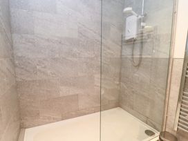A shower with glass panel and tiles at Well Cottage Nr Malmesbury