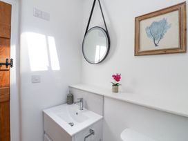 A bathroom with a white sink vanity mirror and framed artwork at Carines Barns - Pen in Cubert