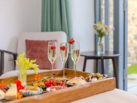 A wooden tray with food and champagne glasses at Carines Barns - Pen, Cubert
