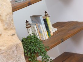 A shelf with books and decorative items at Carines Barns - Pen in Cubert