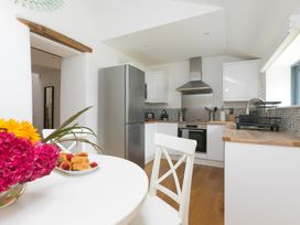 A kitchen with appliances and a dining table at Carines Barns - Pen in Cubert