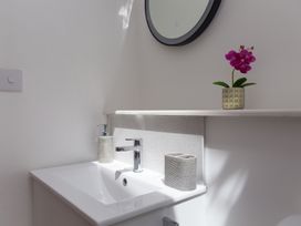 A sink with a mirror and flower pot at Carines Barns - Pen in Cubert