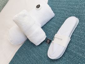 Towels and slippers on a teal surface at Carines Barns - Pen in Cubert