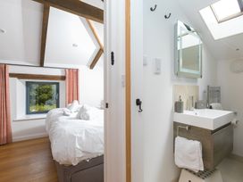 A bedroom with a bed and window leading to an adjoining bathroom at Carines Barns - Pen, Cubert