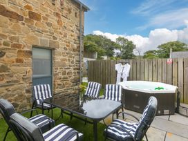 An outdoor seating area with a table and hot tub at Carines Barns - Pen in Cubert