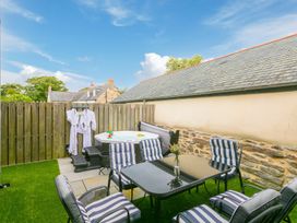 An outdoor area with a jacuzzi and dining table at Carines Barns - Pen in Cubert