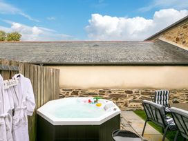 An outdoor area with a hot tub and seating at Carines Barns - Pen, Cubert