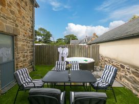 An outdoor area with seating and a hot tub at Carines Barns - Pen Cubert
