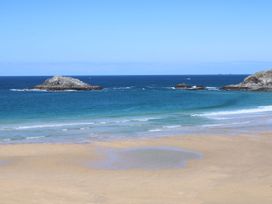 A beach with rock formations and ocean at Carines Barns - Cubert