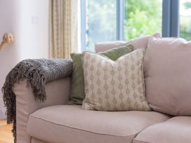 A sofa with cushions and a throw blanket at Carines Barns - Wesley Barn in Cubert