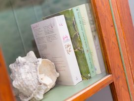 A shelf with books and a shell at Carines Barns - Wesley Barn, Cubert