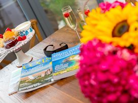 A table with magazines, glasses, scones, jam, strawberries, and flowers at Carines Barns - Wesley Barn in Cubert