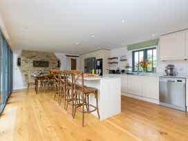 A kitchen with a dining table and kitchen island at Carines Barns - Wesley Barn in Cubert