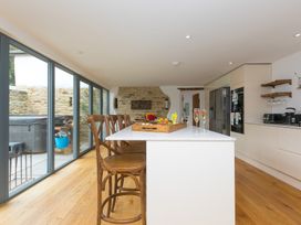 A kitchen with a kitchen island and bar stools at Carines Barns - Wesley Barn in Cubert