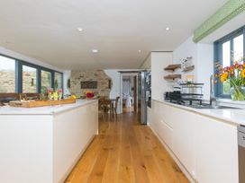 A kitchen with an island and stone wall at Carines Barns - Wesley Barn Cubert