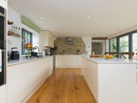 A kitchen with a stone wall and kitchen island at Carines Barns - Wesley Barn, Cubert