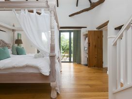 A bedroom with a four-poster bed and large doors to an outdoor area at Carines Barns - Wesley Barn in Cubert