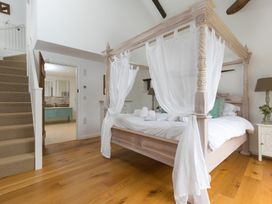 A bedroom with a four-poster bed and staircase at Carines Barns - Wesley Barn, Cubert