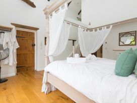 A bedroom with a canopy bed and wooden door at Carines Barns - Wesley Barn in Cubert