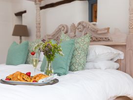 A bedroom with a bed featuring pillows and flowers at Carines Barns - Wesley Barn in Cubert