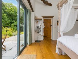 A bedroom with a bed and fan at Carines Barns - Wesley Barn in Cubert