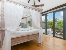 A bedroom with a canopy bed and doors leading to an outdoor area at Carines Barns - Wesley Barn, Cubert