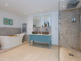 A bathroom with a bathtub, shower, and dual sink at Carines Barns - Wesley Barn in Cubert