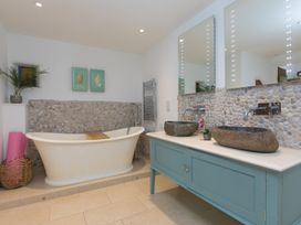 A bathroom with a bathtub and dual stone sinks at Carines Barns - Wesley Barn, Cubert