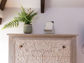 A cabinet with a fern and a mirror on top at Carines Barns - Wesley Barn, Cubert