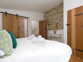 A bedroom with a bed and wooden doors at Carines Barns - Wesley Barn in Cubert