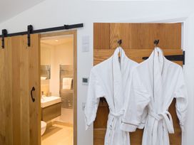 A bathroom with a sliding door and robes hanging at Carines Barns - Wesley Barn in Cubert