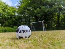 A soccer ball on grass with a goal in the background at Carines Barns - Wesley Barn, Cubert