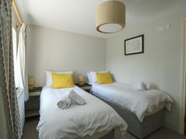 A bedroom with two single beds with yellow pillows and rolled towels at Gwalia Cottage in Brynsiencyn