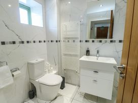 A bathroom with a toilet sink mirror towel radiator and window at Gwalia Cottage in Brynsiencyn