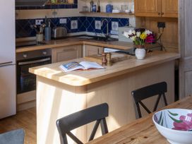 A kitchen with an island, utensils, and a dining table at The Barn in Dittisham