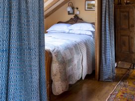 A bedroom with a bed and curtains at The Barn in Dittisham