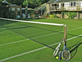 A tennis court with a net and rackets at The Barn in Dittisham