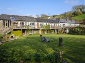 A garden with a building and chairs at The Barn in Dittisham