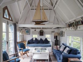 A living room with a model sailboat and comfortable seating at The Folly in Dittisham