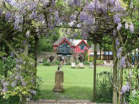 A garden with a view of a house through an archway at The Folly in Dittisham