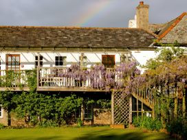 A building with a balcony and wisteria at Wisteria Suite in Dittisham