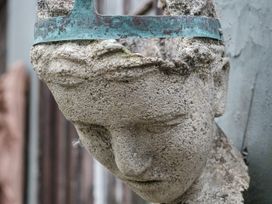 A decorative head sculpture in a garden at Wisteria Suite in Dittisham