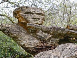 A wooden sculpture of a human figure in a natural outdoor setting