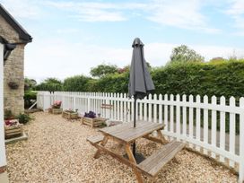 A garden with a wooden table and umbrella at The Cottage in Ettington