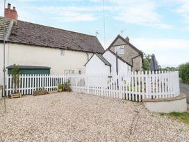 An outdoor area with a house and white picket fence at The Cottage in Ettington